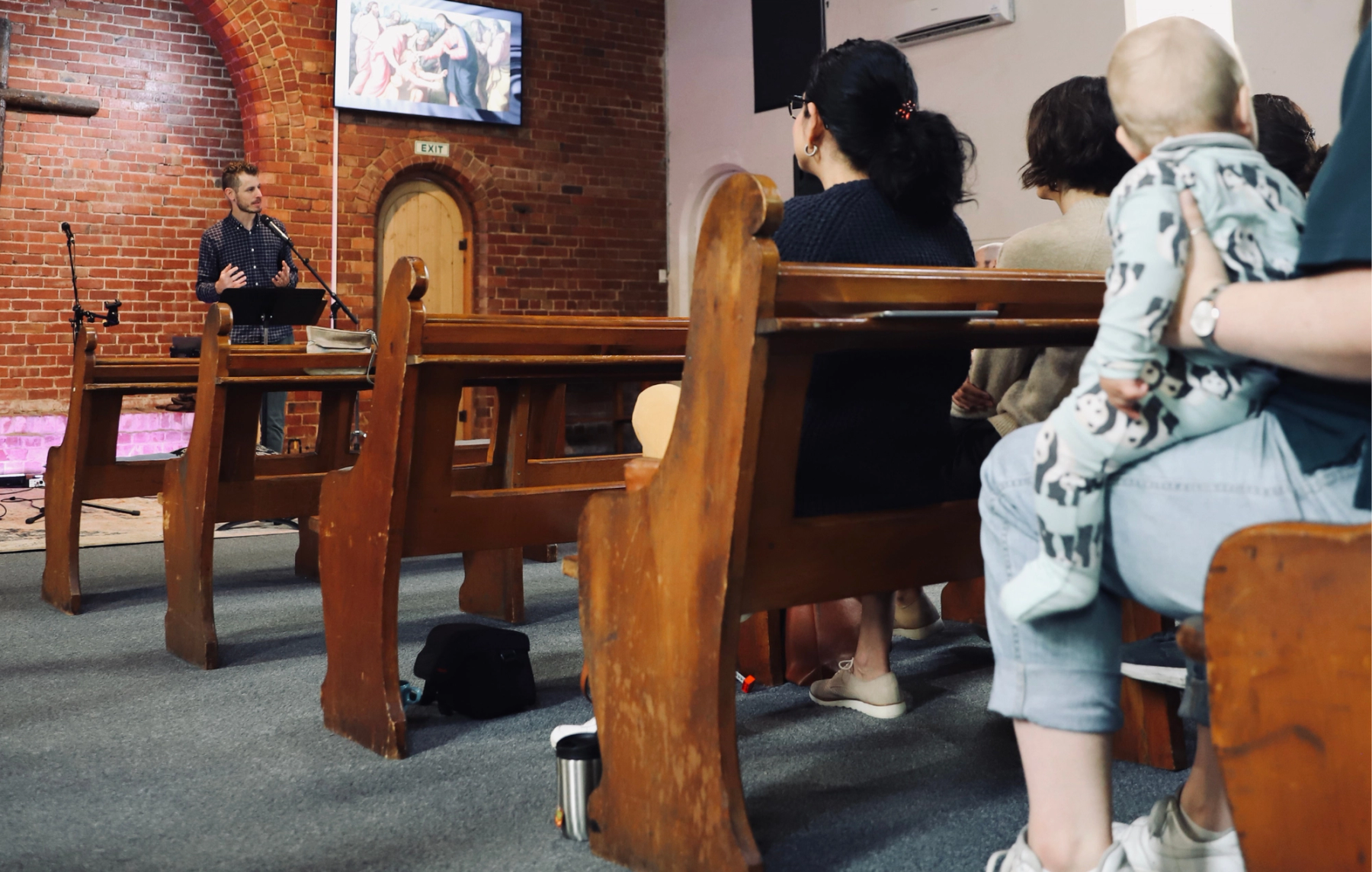 A group of people sitting in a church building listening to a preacher.